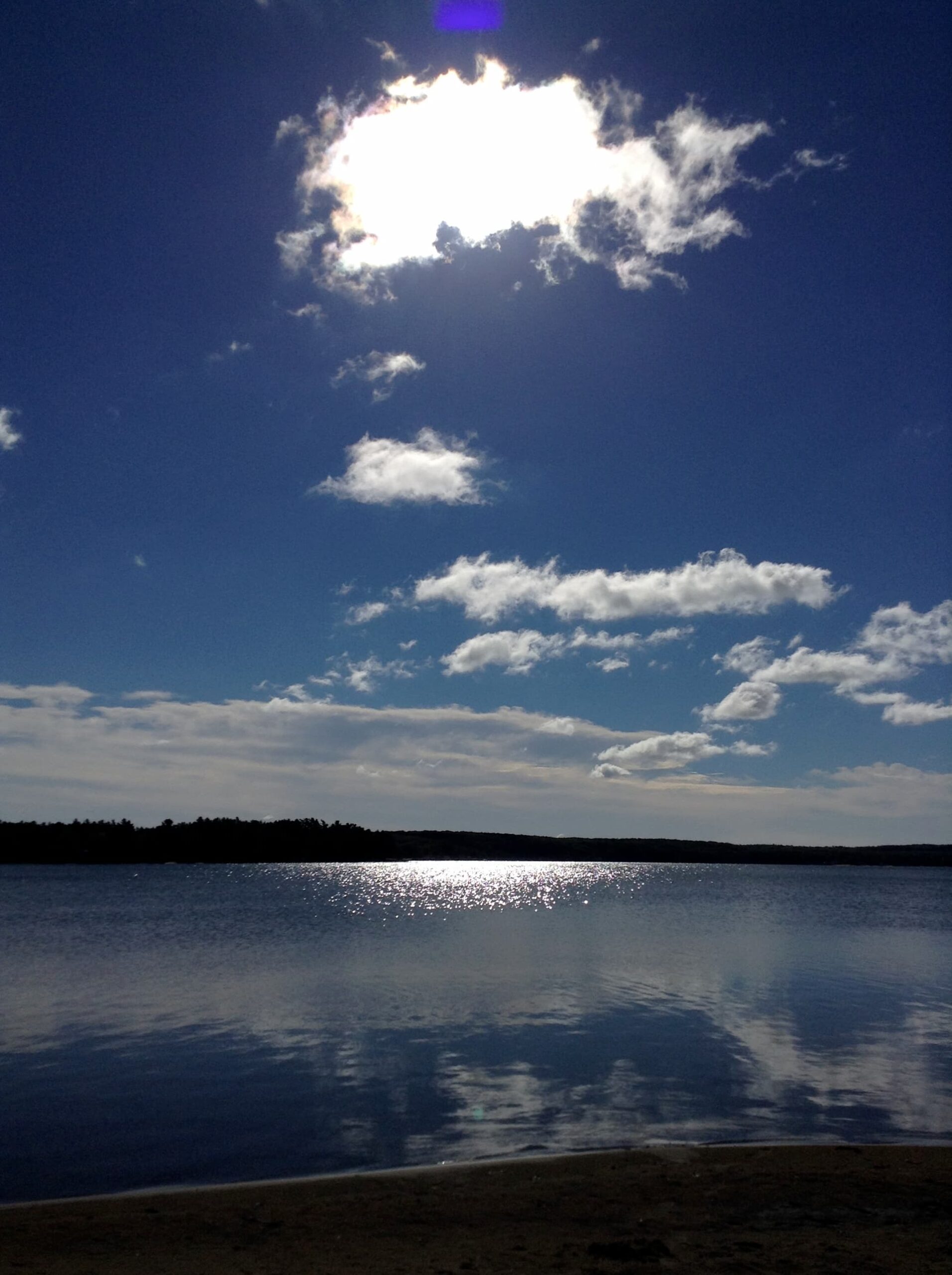 white clouds in a blue sky over a calm lake